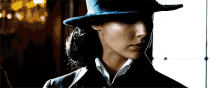 a close up of a woman wearing a hat and a suit