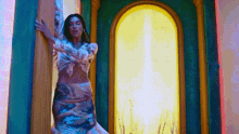 a woman in a crop top and skirt is standing in front of a window in a room .