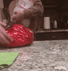 a person is wrapping a bag of food in red foil on a counter .