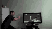 a man is pointing at a tv screen that says ' photo camera '
