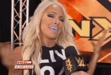 a woman is talking into a microphone while wearing a black shirt that says liv