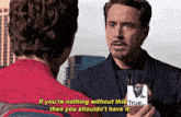 a man in a suit is talking to another man in a red shirt who is holding a picture of tony stark ..