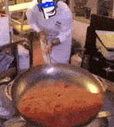 a chef is stirring a pan of sauce with a smiley face drawn on his head