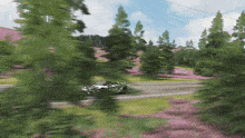 a white car is driving down a road surrounded by trees