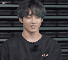 a young man with green hair is wearing a black shirt with the word fila on it .