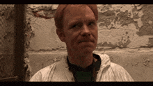 a man with red hair is wearing a white coat and a green shirt