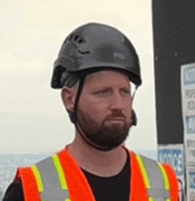 a man wearing a black helmet and an orange vest .