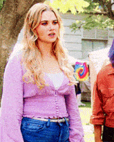 a blonde woman wearing a purple top and jeans