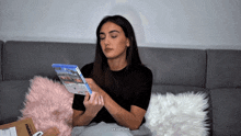 a woman is sitting on a couch holding a video game and a box that says walmart