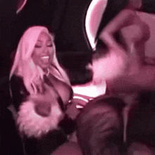 a woman in a pink dress is dancing in a dark room with a group of people .