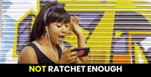 a woman wearing headphones looks at her phone with the words not ratchet enough above her