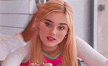 a blonde woman is sitting at a table eating a cupcake .