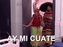 a man and a woman in mexican costumes are standing in a doorway with the words ay mi cuate written on the bottom