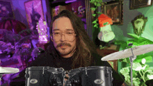 a man with long hair and glasses is playing a drum set