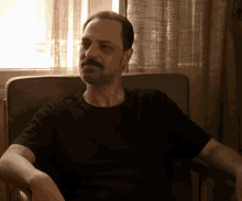 a man with a mustache is sitting in a chair