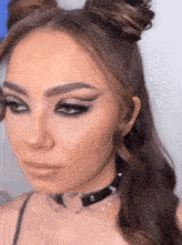 a close up of a woman 's face wearing a choker and buns