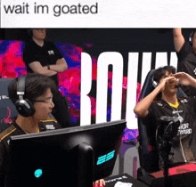 a man wearing headphones sits in front of a monitor with the words " wait im goated " written above him