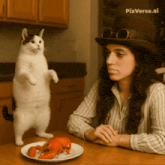 a woman sitting at a table looking at a plate of lobster and a cat standing on its hind legs