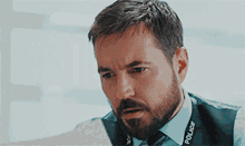 a man with a beard is wearing a police lanyard around his neck