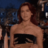 a woman with red hair is holding a piece of paper and making a face .