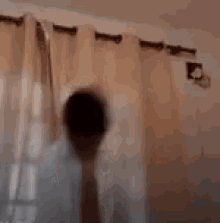 a blurry picture of a person standing in front of a window in a room .