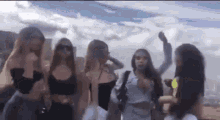 a group of young women are standing next to each other in front of a blue sky .