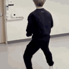 a man in a black sweater and black pants is standing in a room .