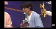 a man is holding a trophy and talking into a microphone while standing on a stage .