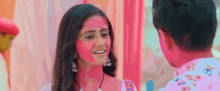 a man and a woman are standing next to each other and smiling . the woman is wearing pink powder on her face .