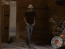 a man wearing a hat and a black shirt is walking in front of a sign that says " contenido de la "