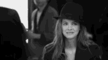 a black and white photo of a woman wearing a fedora .