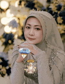 a woman wearing a hijab and a crown holds a diamond