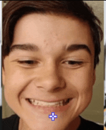 a close up of a boy 's face with a blue cross in the middle of his mouth
