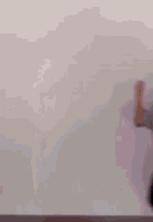 a woman in a purple shirt and jeans is dancing in front of a white wall .