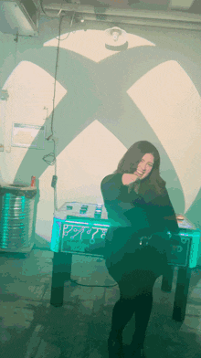 a woman stands in front of a xbox logo