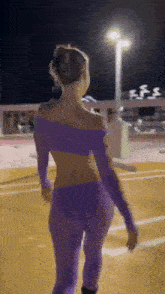 a woman in a purple top and purple pants is walking down a street .