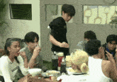 a group of people sitting around a table with one wearing a shirt that says " supreme "