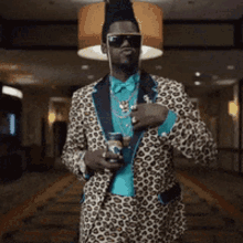 a man in a leopard print suit and sunglasses holds a can of beer