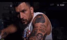 a man with a lot of tattoos on his arms is on a wrestling show on cw