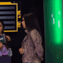 a woman in a snake print jacket is standing in front of a green sign that says ' ain ' on it