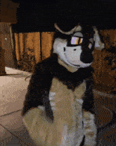 a person in a furry wolf costume is standing on a sidewalk in front of a wooden fence