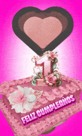 a pink cake with the number 1 on top and the words feliz cumpleanos on the bottom