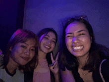 three women are posing for a picture and one of them is giving the peace sign