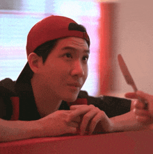 a man wearing a red baseball cap is looking at something