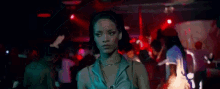 a woman in a green dress is standing in a crowd of people in a club .