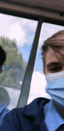 a man wearing a mask on a bus looks out the window