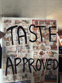 a person holding a newspaper with the words taste approved on it