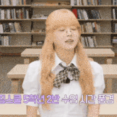 a girl with blonde hair and glasses is sitting at a desk in a library
