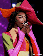 a woman wearing a colorful hat and gloves is covering her mouth
