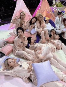 a group of women are laying on pillows in front of a pink teepee